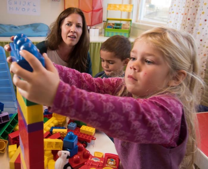 Kvinne og to barn leker med duplo.