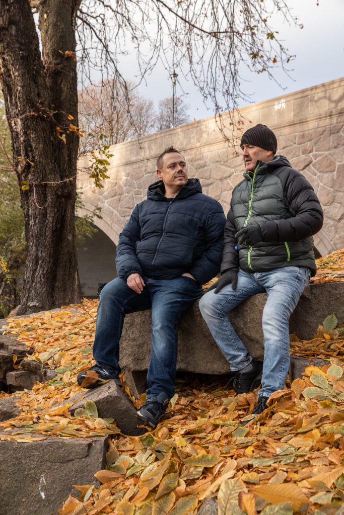 To menn sitter på stein i en park og snakker.