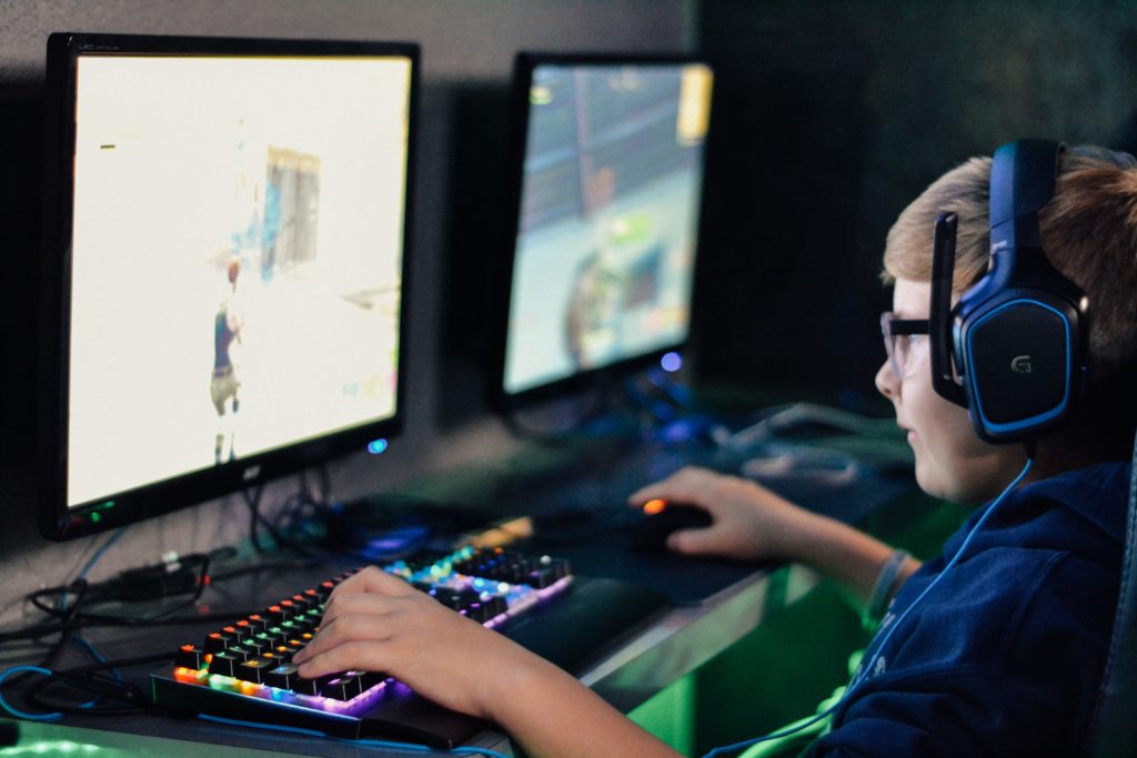 Gutt som sitter med headset og gamer på en PC. Det sitter to gutter der og gamer.
