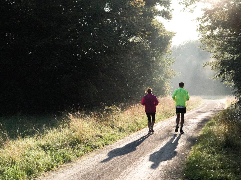En mann og en dame som løper ute i skogen