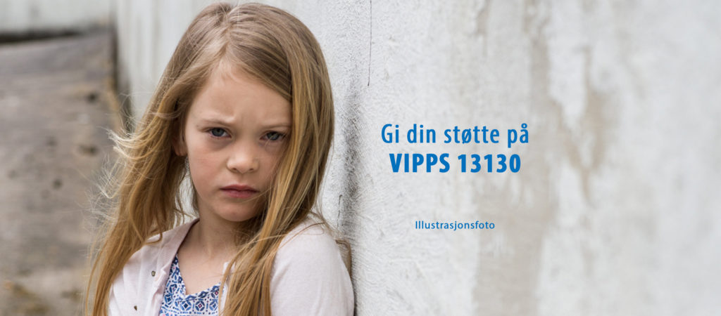 Liten jente med langt hår inntil en vegg