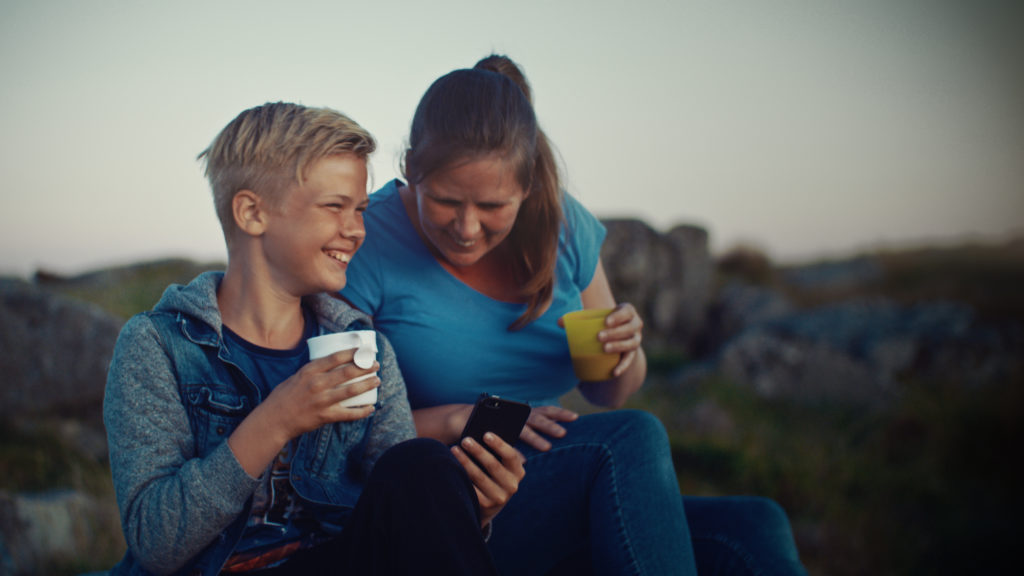 Kvinne og gutt ler og ser sammen på mobil