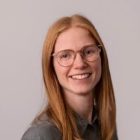 Kvinne smiler, hun har på seg briller og en grønn bluse