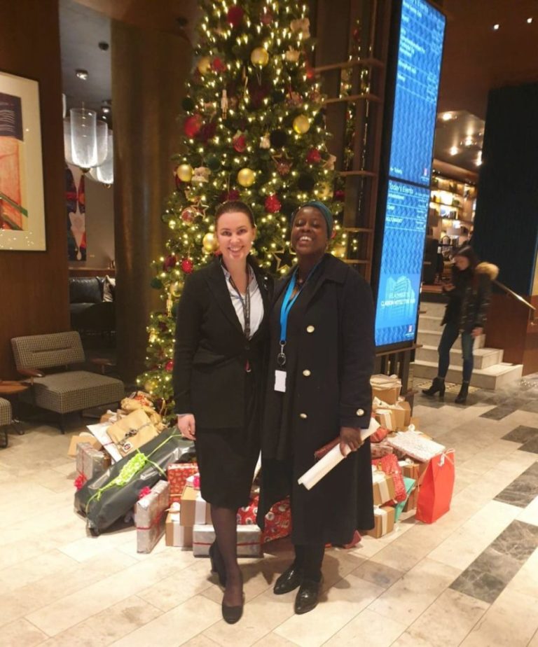 To personer står foran et juletre med mange pakker under på Clarion Hotel the hub