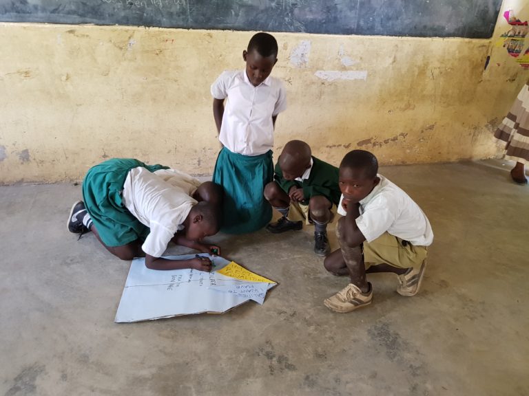 Barn på gulvet i et klasserom i Kenya