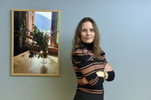 Ailin Strømsholm i Blå Kors står mot en vegg med et fint bilde ved siden av seg