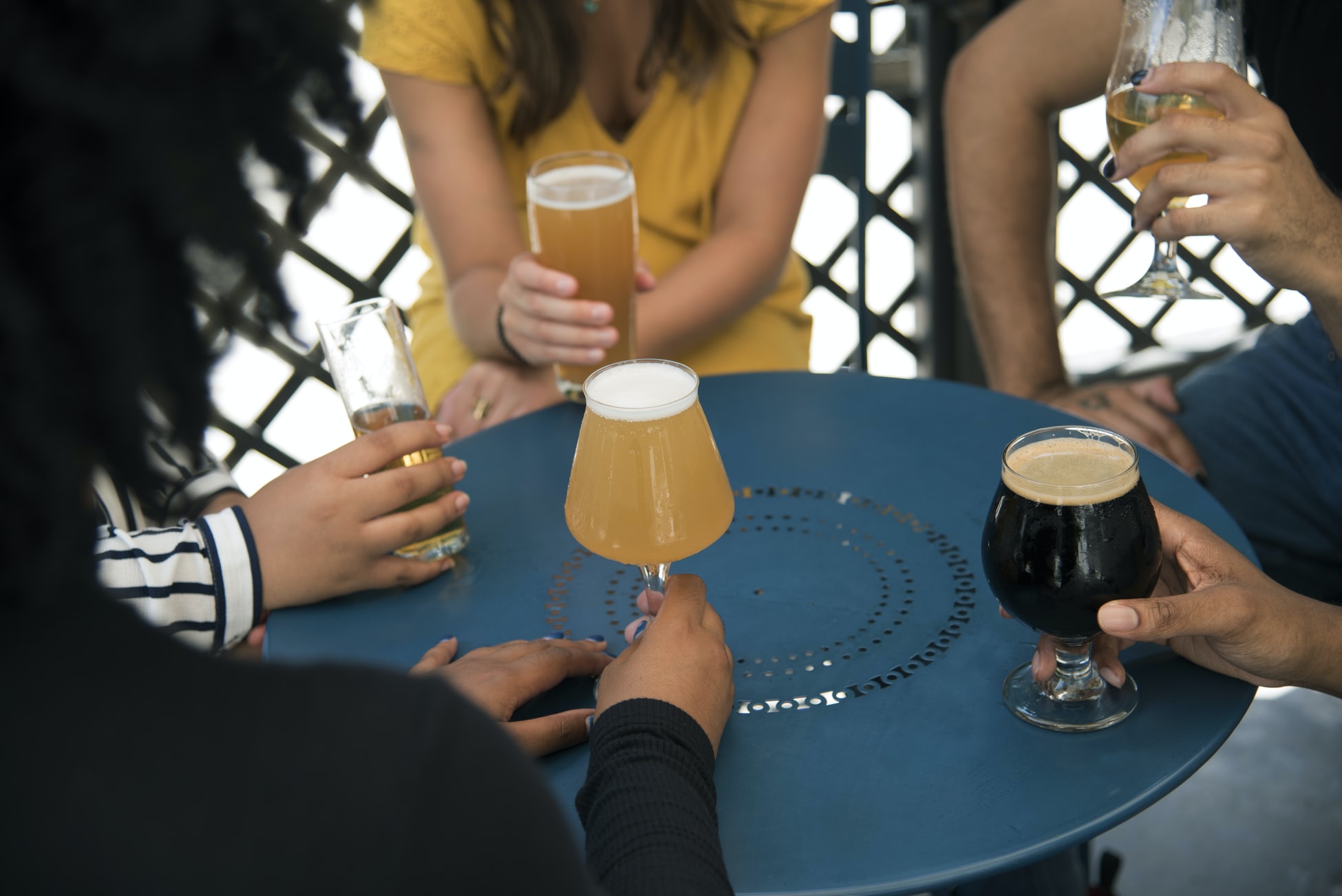 Et bått bord med 5 mennesker rundt og glass med ulike typer øl.