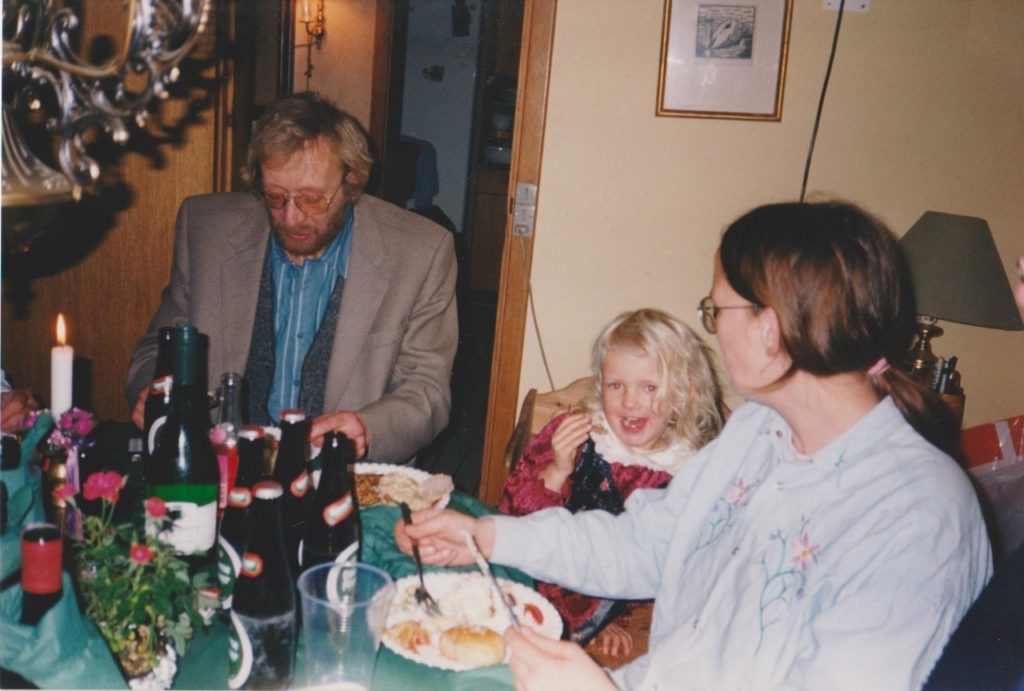 To voksne og barn som sitter rundt et bord i julen. mange flasker på bordet