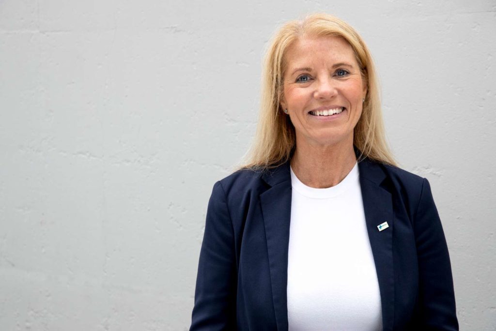 Trine Stensen generalsekretær i Blå Kors smiler foran en vegg. Hun har på seg en mørkeblå dressjakke