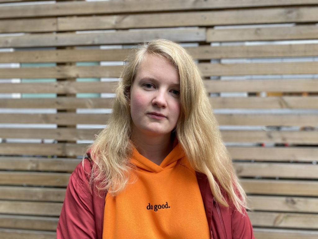 Voksen jente med langt hår og orange genser