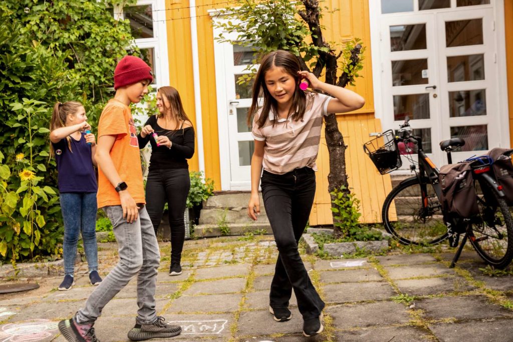 Barn leker ute i gården foran Barnas Stasjon.