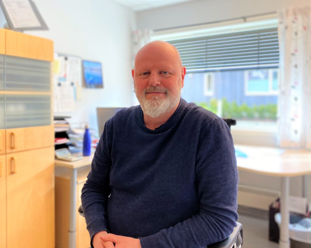 Direktør Jens Røed sitter på kontoret sitt ikledd blå genser og smiler til kamera.
