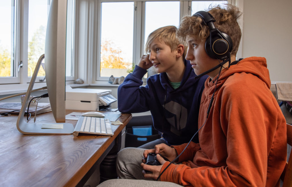 To gutter i 10-12 år alderen ser konsentrert bort på skjermen mens de gamer