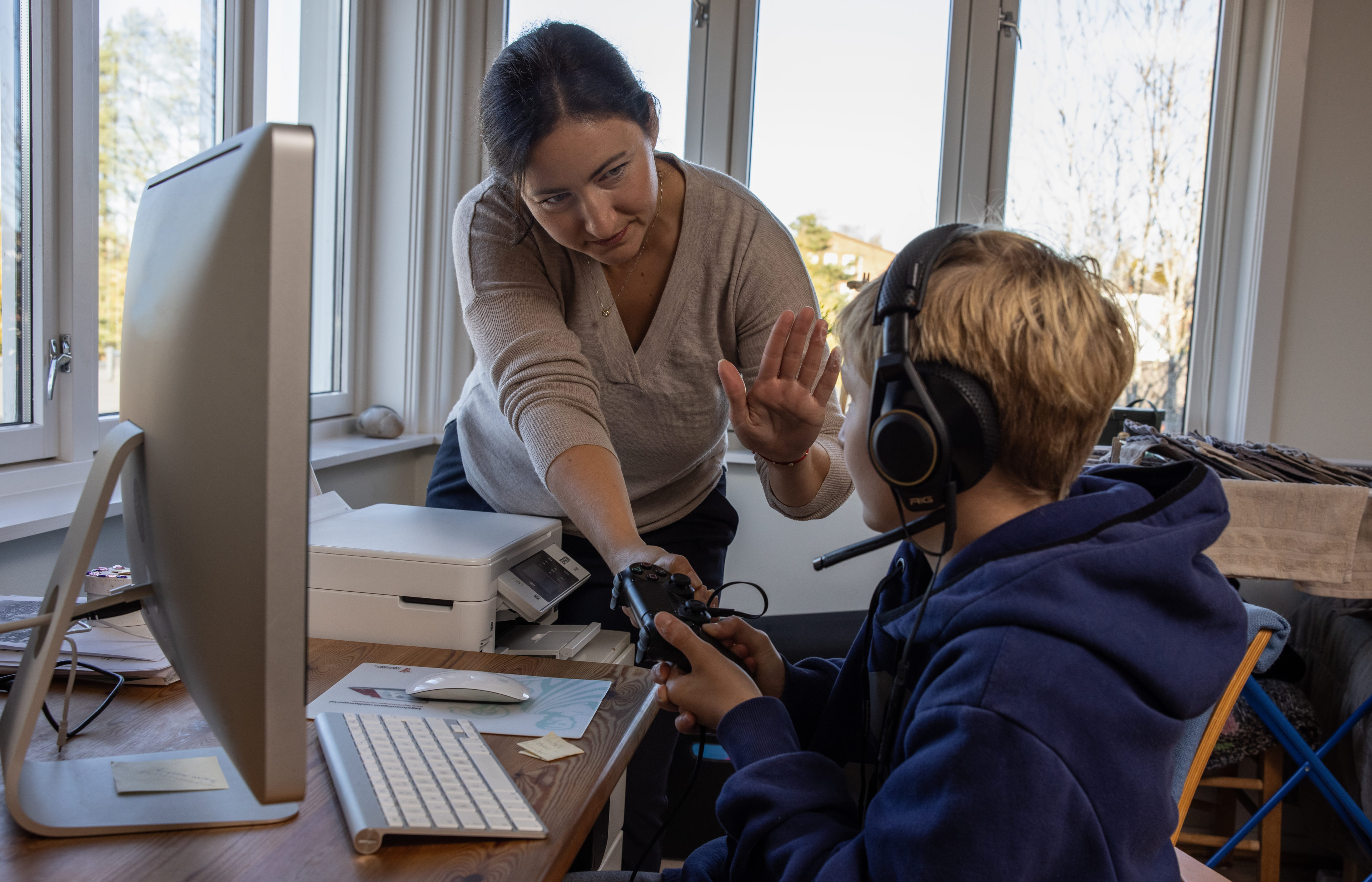 En mamma viser stopp med håndflaten mens sønnen gamer