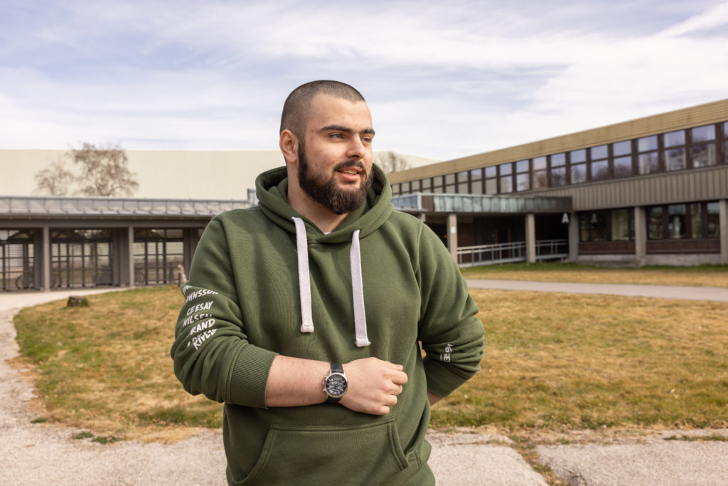 Mansor Abubakarov står i skolegården med grønn russegenser