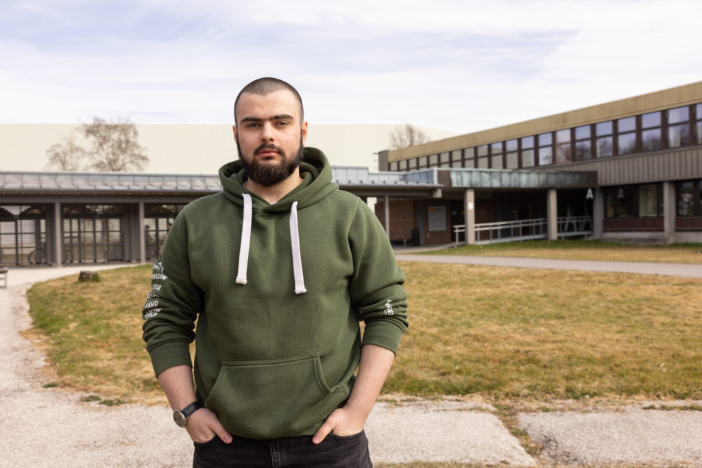 Mansor Abubakarov står i skolegården med grønn russegenser