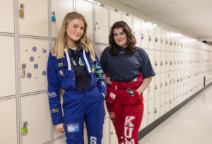 To jenter står inntil et skap på skolen. De står med russedress, en i blått og en i rødt