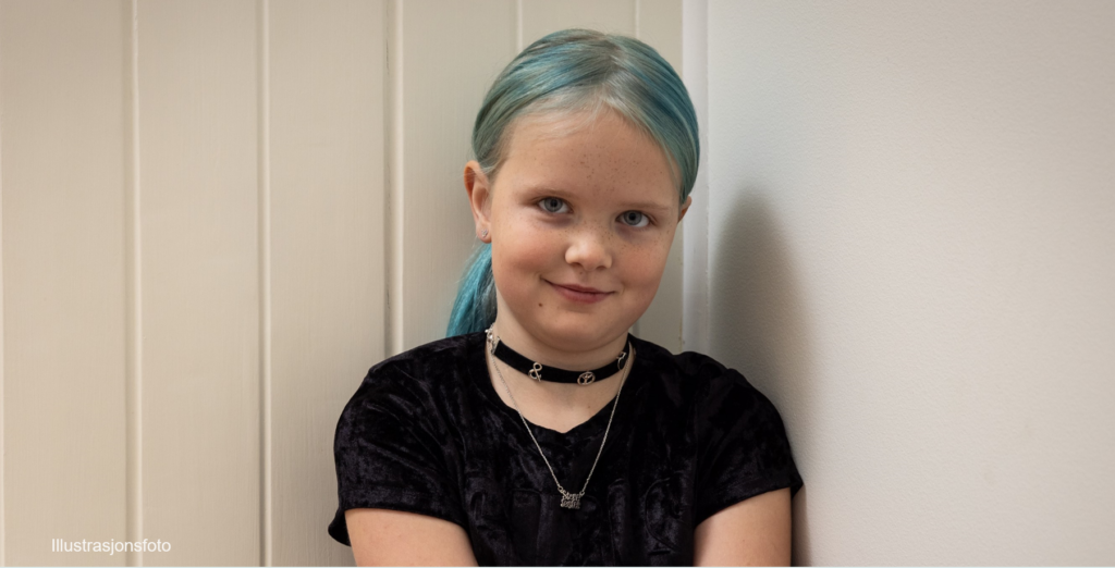 jente ser i kameraet og smiler forsiktig