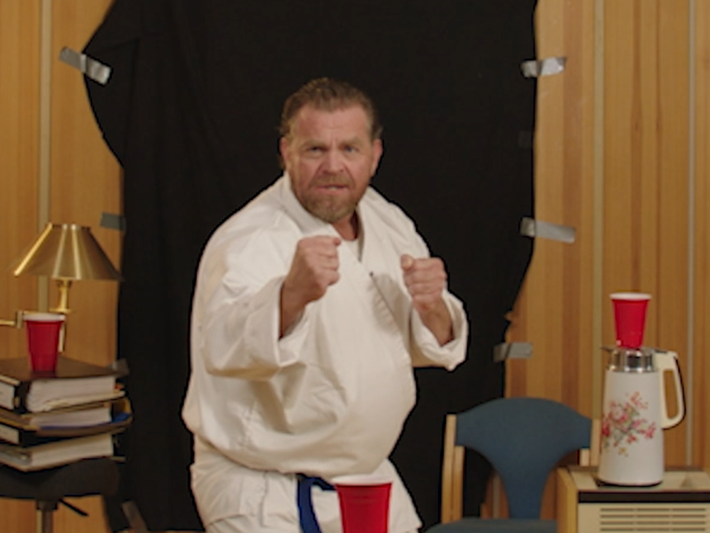 Mann i hvit karatedrakt demonstrerer karateposisjon