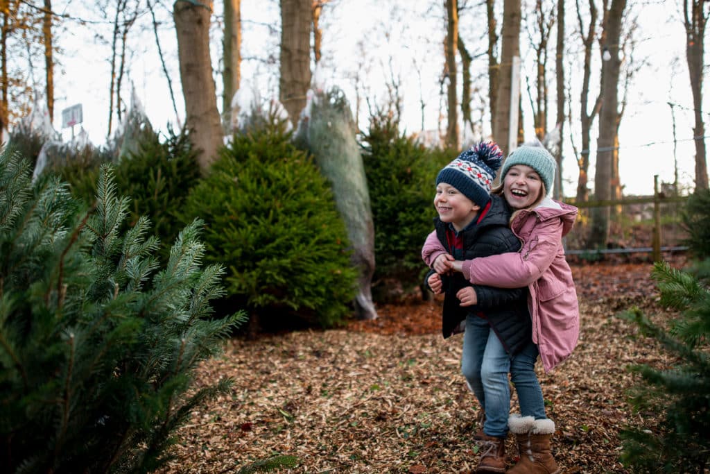 A young boy and girl wearing warm clothing playing at a Christmas market in Northeastern England. They are in the festive spirit and being mischievous.