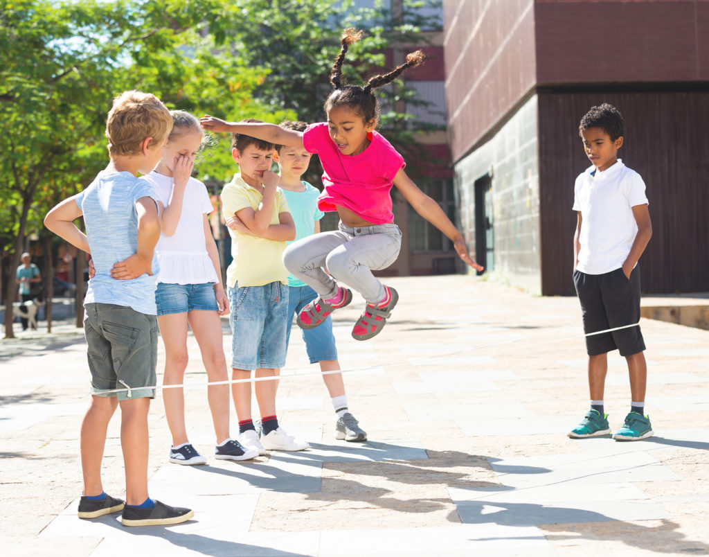 Barn hopper tau i skolegården. Bildet illustrerer barn som leker sammen i en aktivitet som frivillig tidgiver kan hjelpe med.