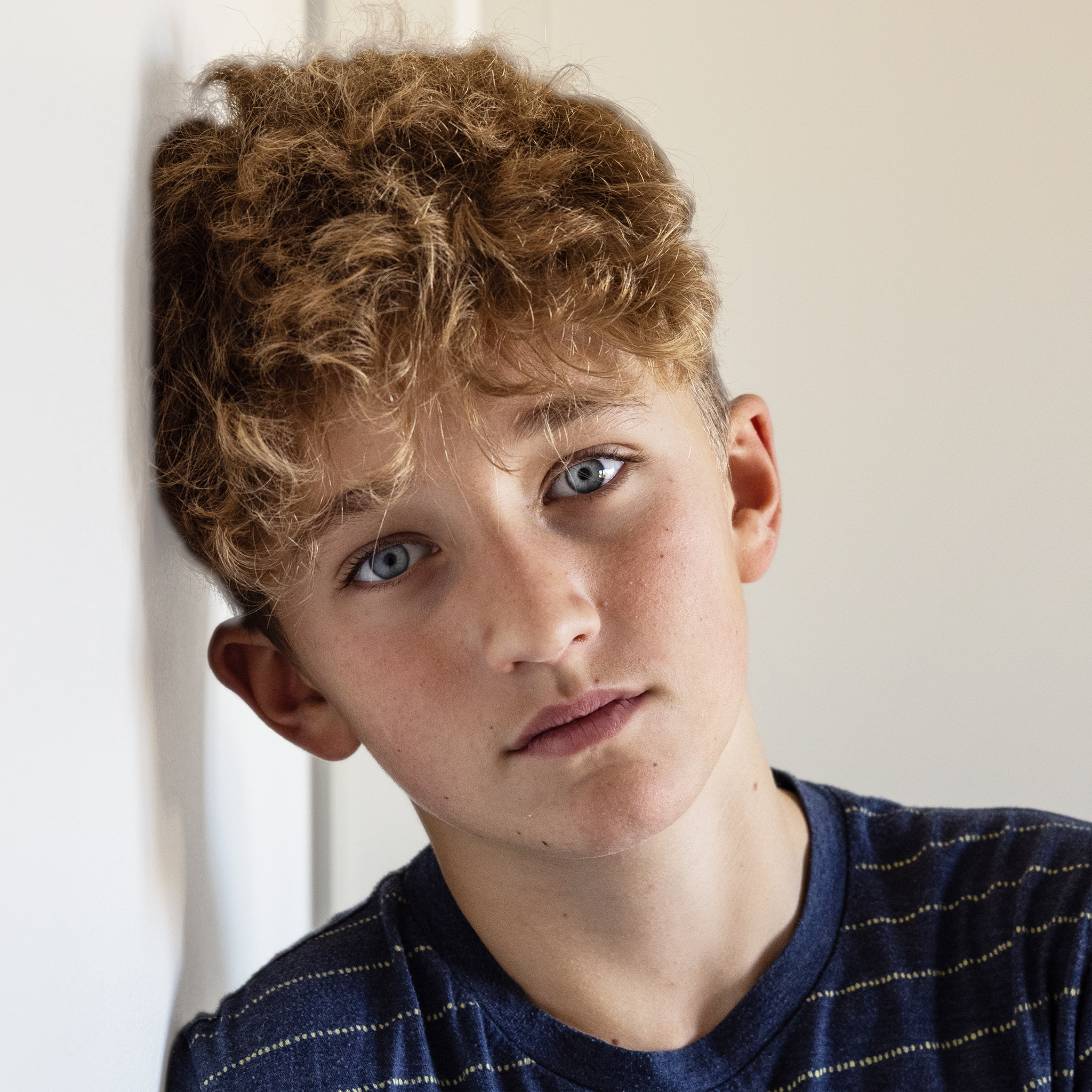 Gutt med brunt hår og blå øyne ser inn i kamera.