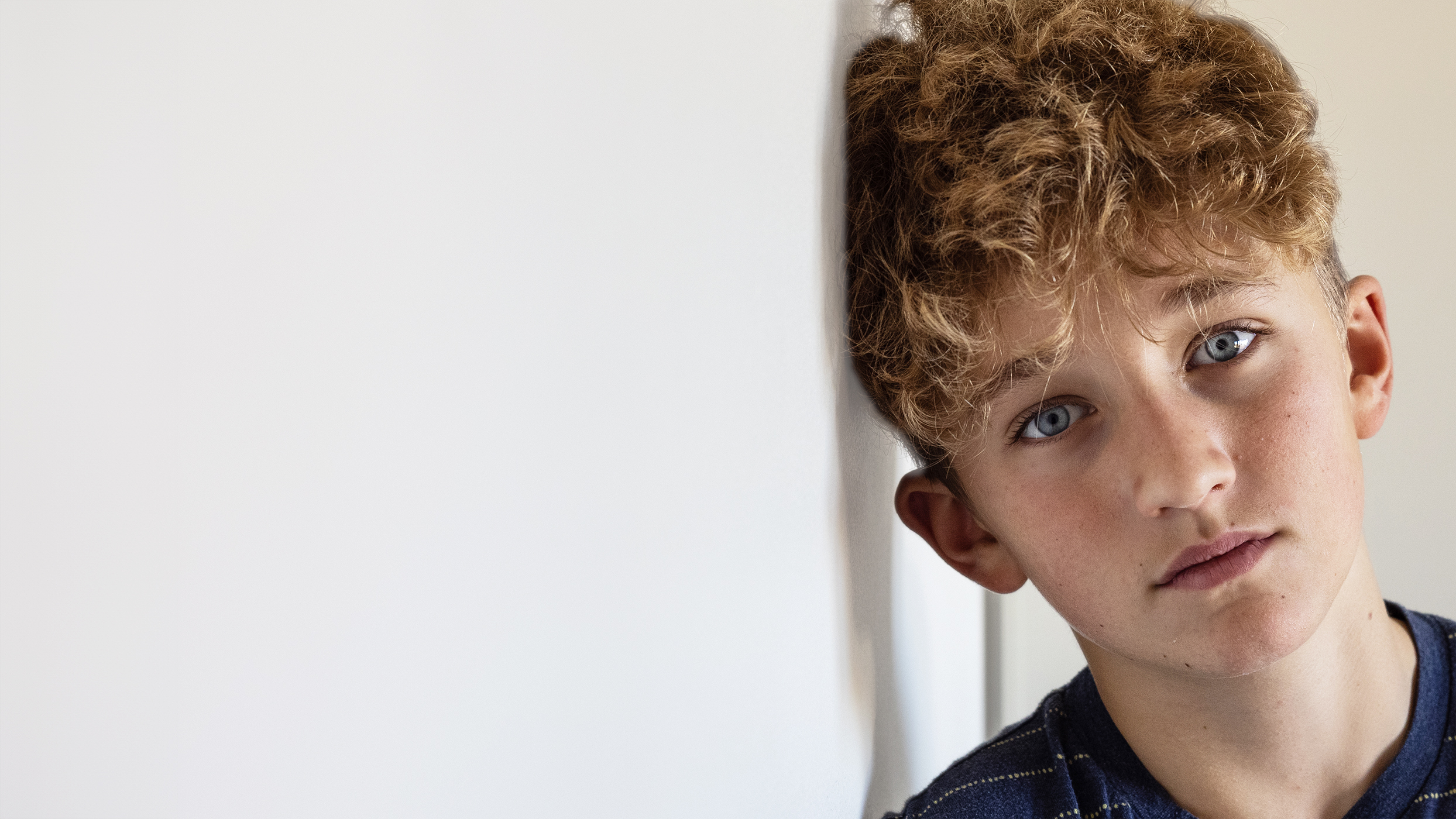 Gutt med brunt hår og blå øyne ser inn i kamera.