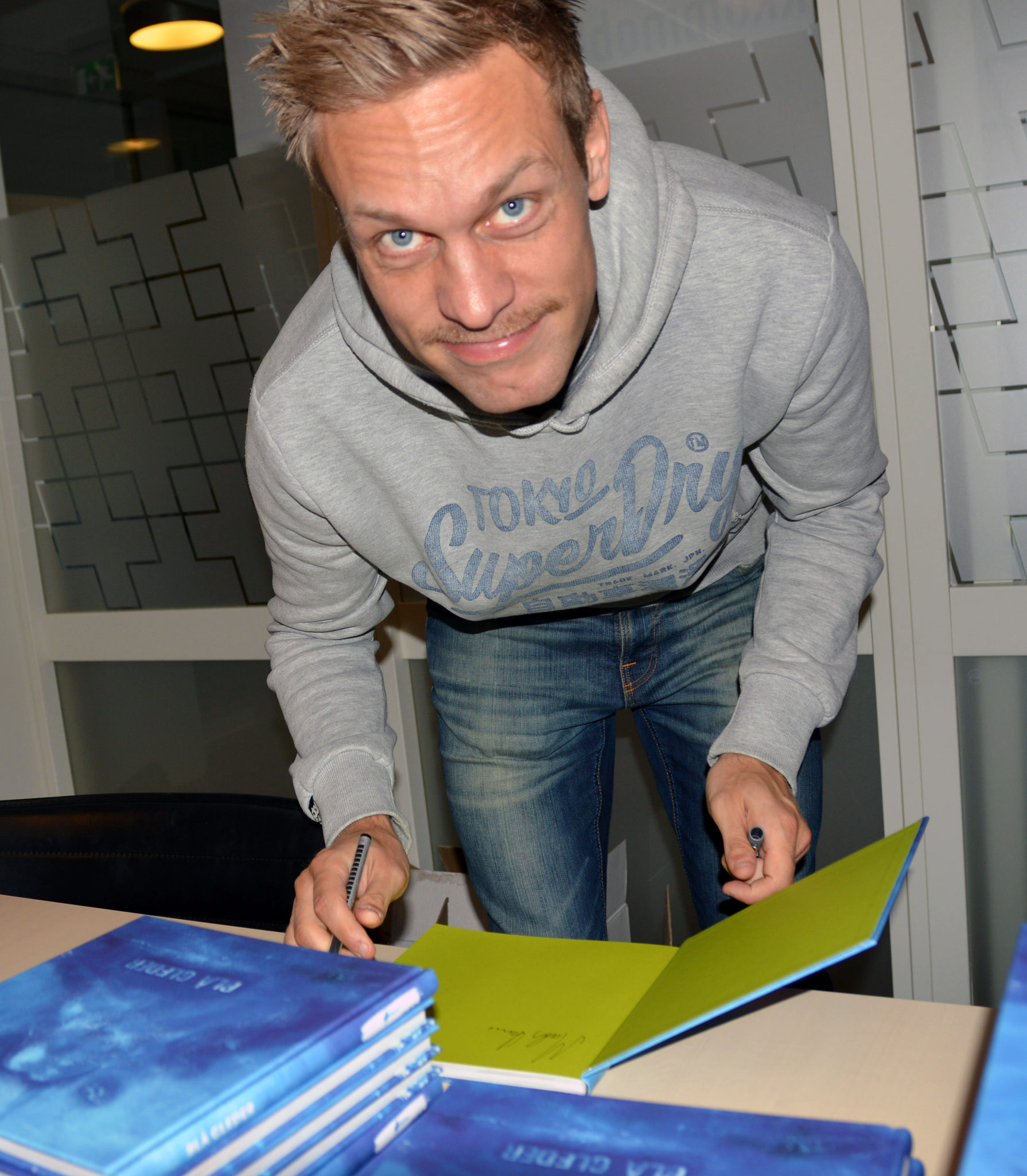 Samtlige deltakere signerte flere eksemplarer av den nye kokeboken som Barnas Stasjon har utviklet i samarbeid med den kjente mesterkokken Trond Moi, her er Mads Hansen fra Mjøndalen IF i gang med signeringen.