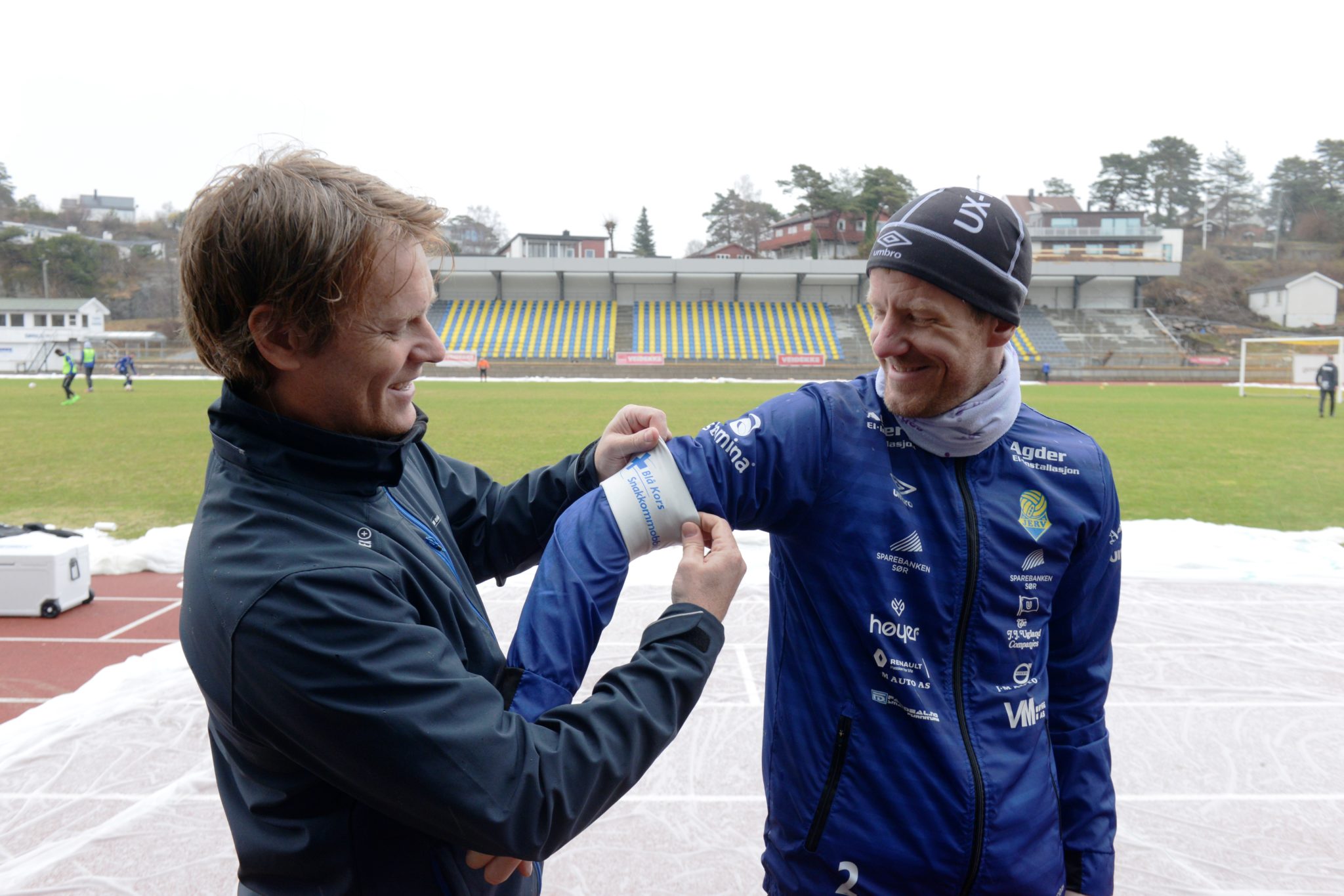 Overlevering: Henning Reme i Blå Kors trer kapteinsbindet på armen til Jerv-kaptein Glenn Andersen etter fredagens økt på regntunge Levermyr. (Foto: Alexander Nupen)