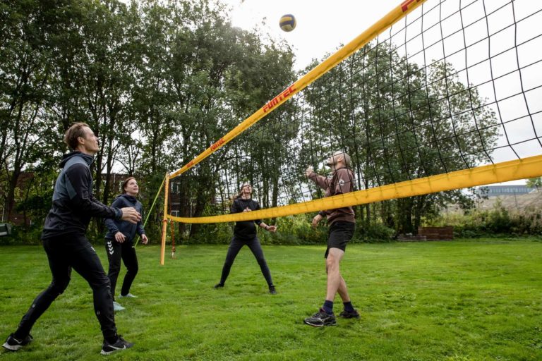 Fire mennesker spiller volleyball og har det gøy