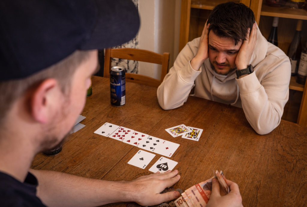 To gutter spiller poker. Den ene sitter med hodet i hendene med et fortvilt ansiktsutrykk etter å ha tapt.