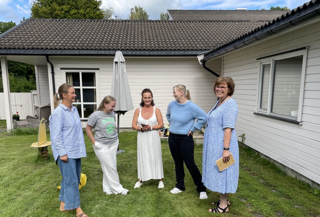 To ansatte har et hyggelig møte i klinikkens hage med tre gjester