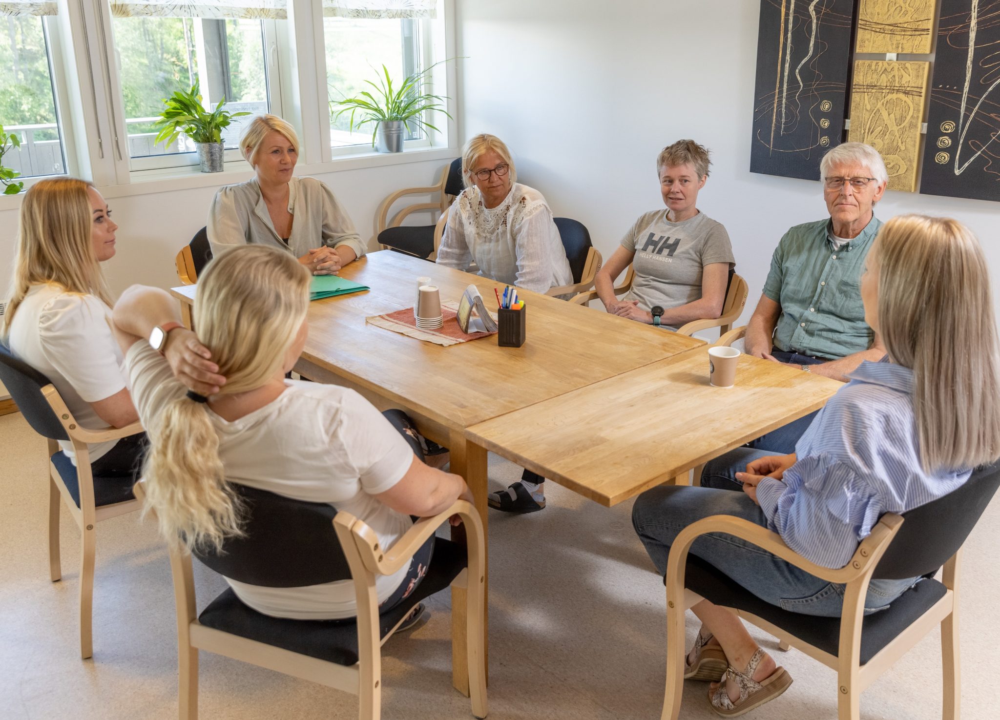 en gruppe mennesker sitter rundt et møtebord