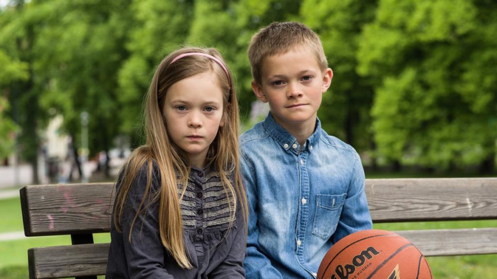 Gutt og jente sitter på en benk og ser alvorlige ut