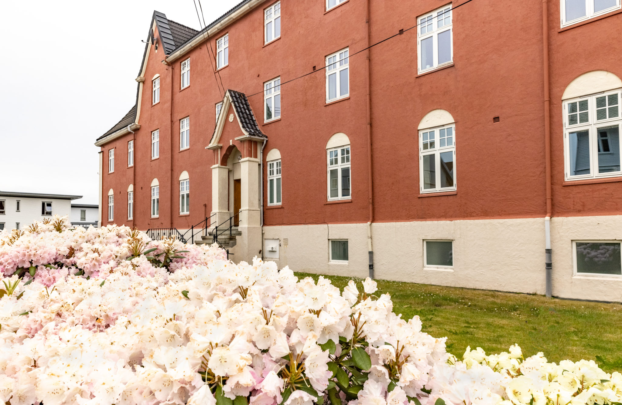 Rødbrunt murbygg og vakre blomster utenfor