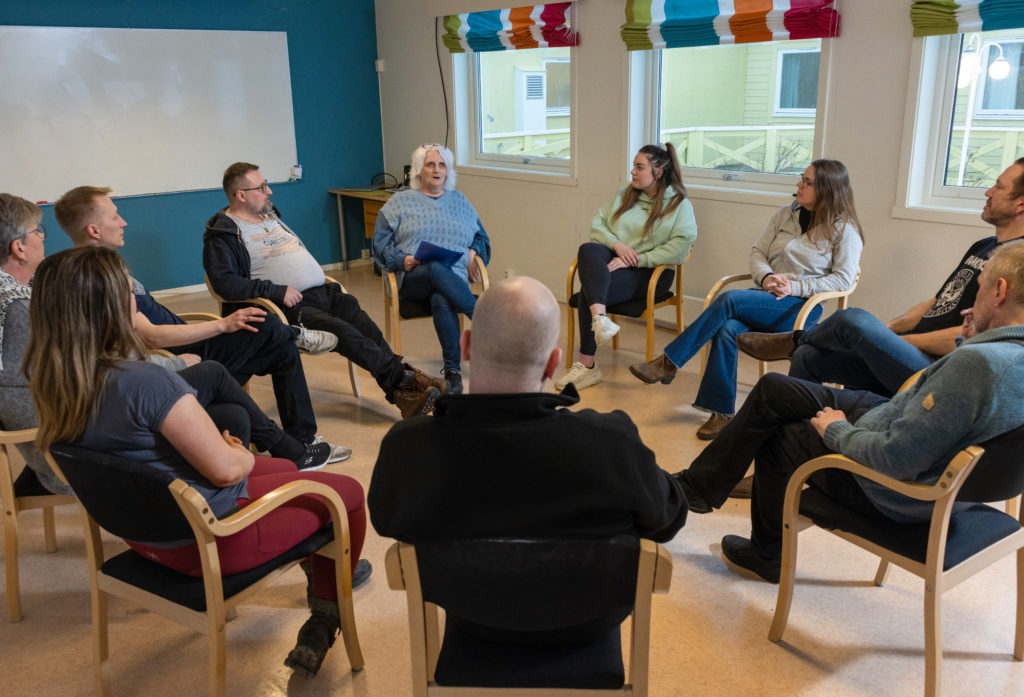 Mange personer sitter i en ring og snakker sammen