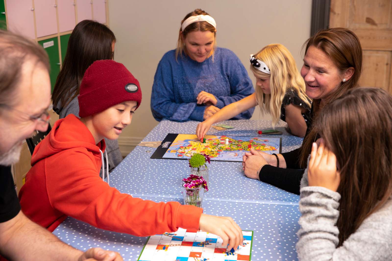 Barn og voksne sitter med spill ved bordet.